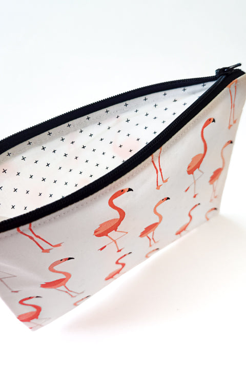 an image of the classic pink flamingos cotton zip pouch that shows the bag unzipped with a view of the lining.  The lining material is 100% cotton and feature mini black cross marks on a white background.