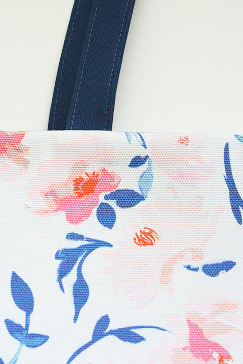 close up detailed view of the oversized tote bag showing part of the dark blue canvas straps and the pink and blue floral watercolor material