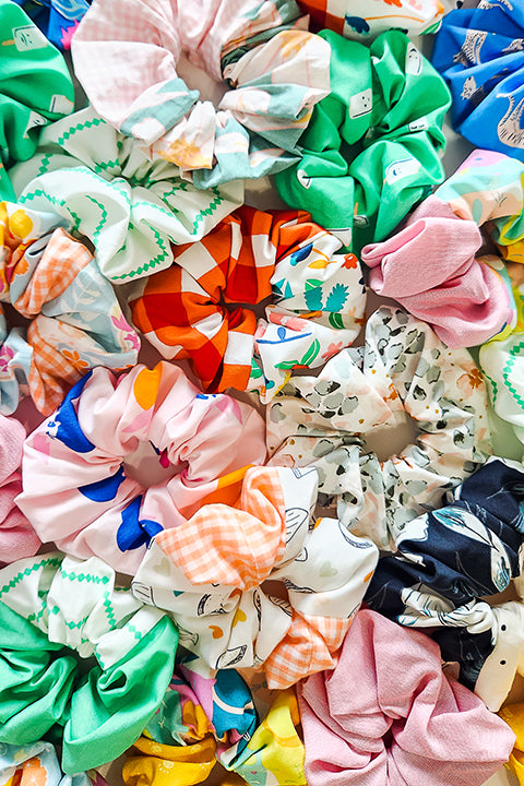 image of a pile of upcycled handmade scrunchies made in a variety of colorful and vibrant cotton prints