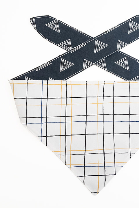 thin plaid print side detailed view of pyramids and grid reversible pet bandana. prints feature black, white, yellow and blue.
