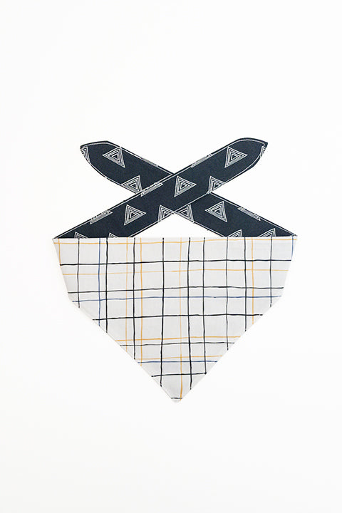 thin plaid print side of pyramids and grid reversible pet bandana. prints feature black, white, yellow and blue.