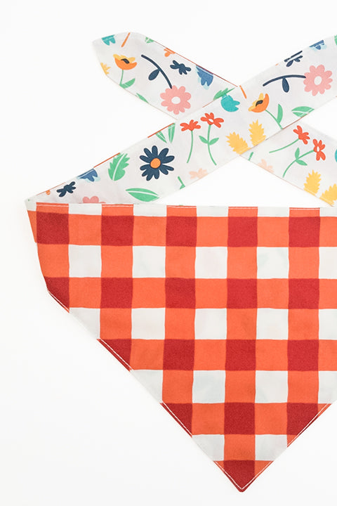 picnic plaid print side detailed view of spring picnic reversible pet bandana. prints feature a colorful floral and red and cream buffalo plaid.
