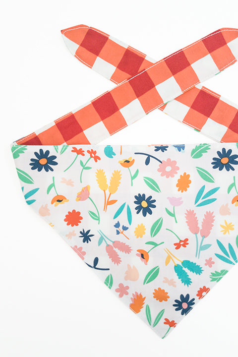 spring floral print side detailed view of spring picnic reversible pet bandana. prints feature a colorful floral and red and cream buffalo plaid.