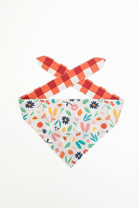 spring floral print side of spring picnic reversible pet bandana. prints feature a colorful floral and red and cream buffalo plaid.