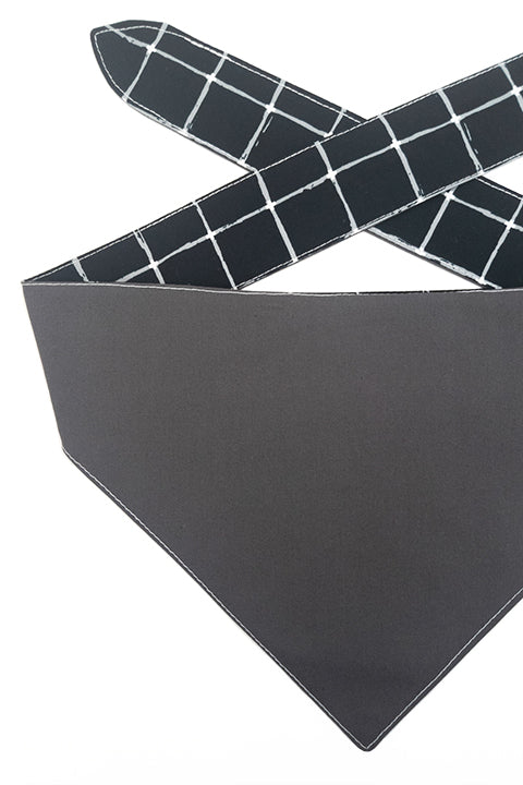 detailed view of a 100% premium cotton reversible pet bandana shown made from a charcoal grey reverse and black and white grid front