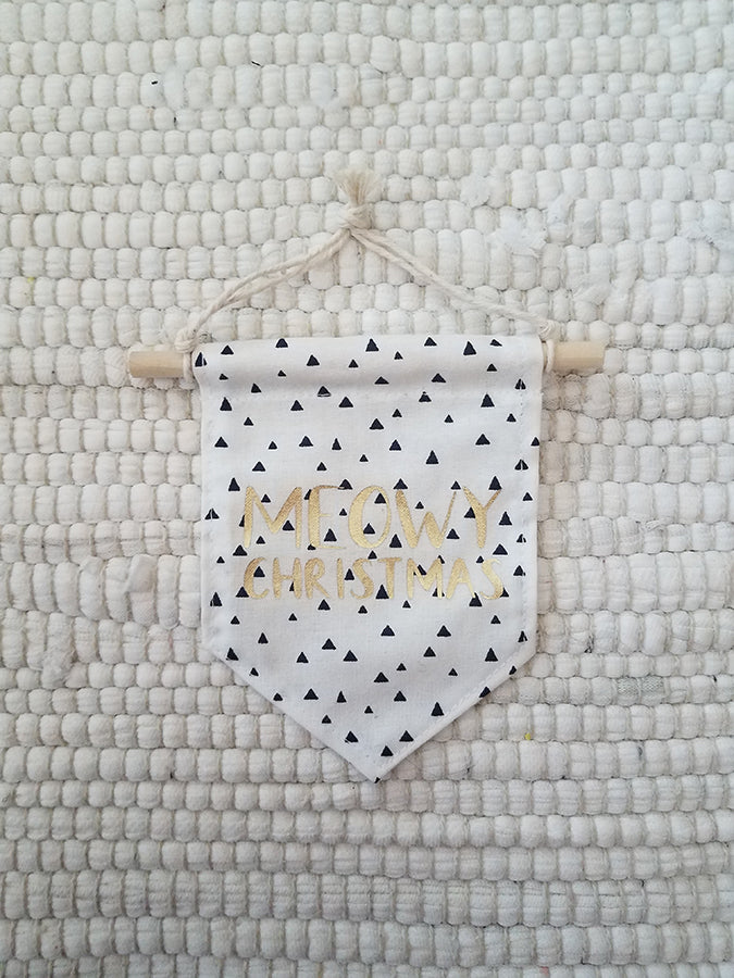 mini handmade pennant ornament featuring white with black triangles fabric printed with gold words saying Meowy Christmas