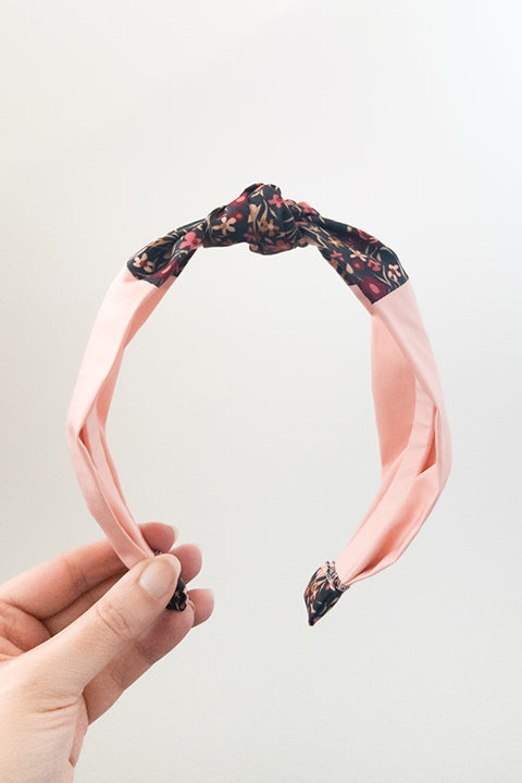 front view of an upcycled handmade headband created with two different scrap fabrics, a blush pink and a mini floral print