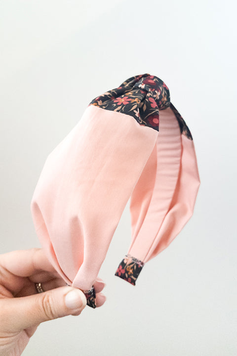 side view of an upcycled handmade headband created with two different scrap fabrics, a blush pink and a mini floral print