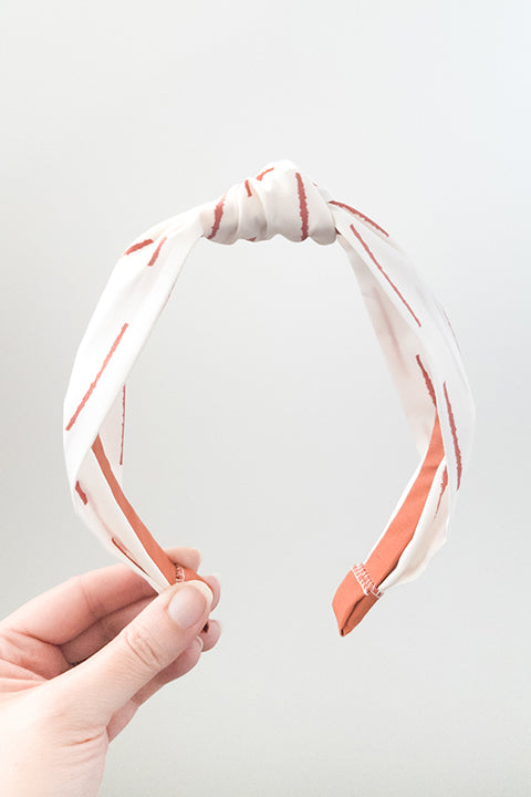 front view of an upcycled handmade headband made from premium cotton fabrics in a rust and off white boho stripe print
