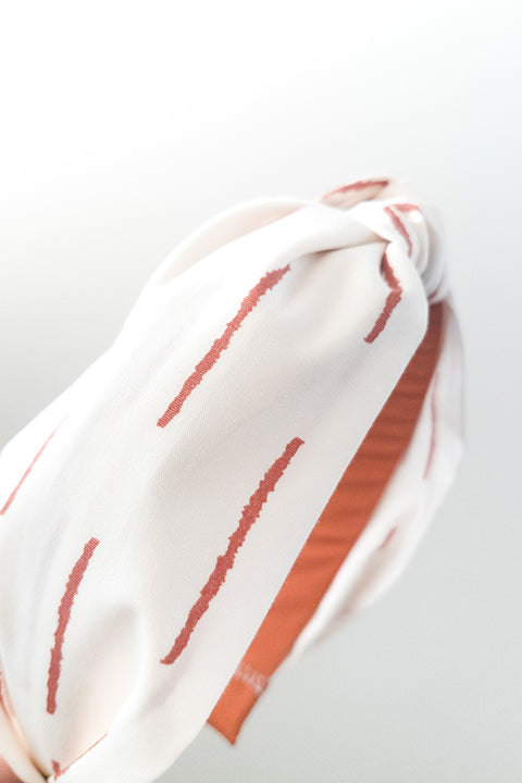 side detailed view of an upcycled handmade headband made from premium cotton fabrics in a rust and off white boho stripe print