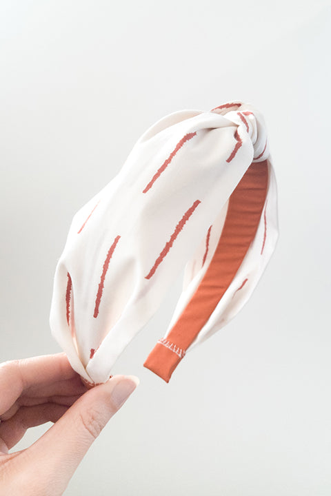 side view of an upcycled handmade headband made from premium cotton fabrics in a rust and off white boho stripe print