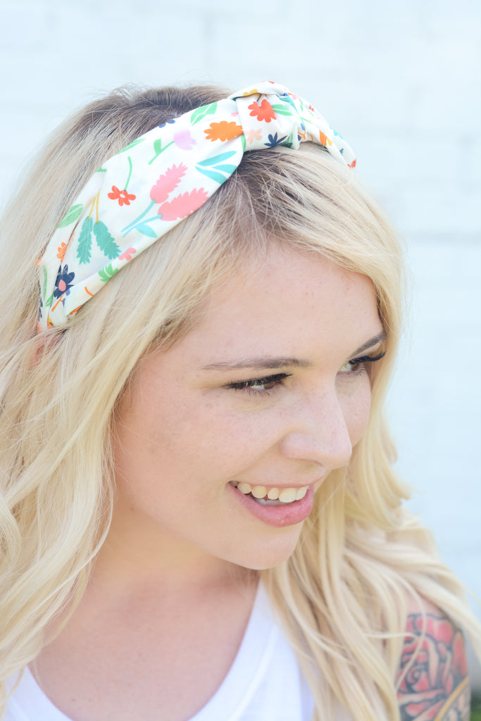young blonde woman modeling cotton top knot head band in rainbow colored bright floral print fabric
