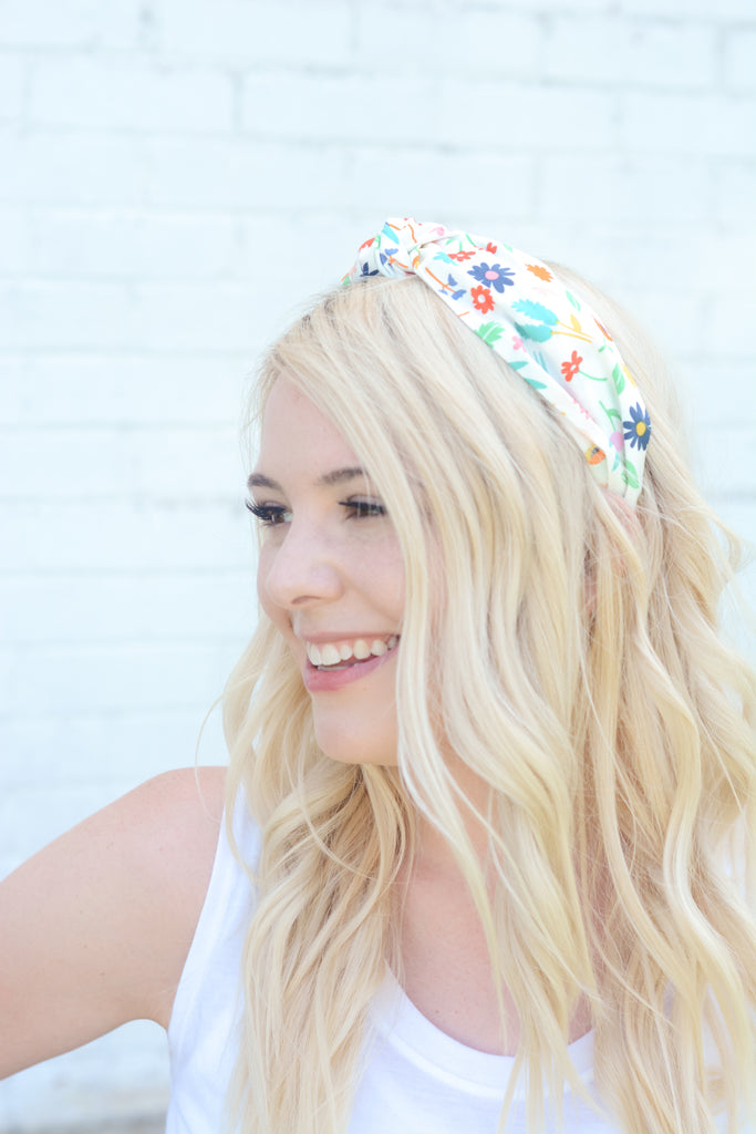 young blonde woman modeling cotton top knot head band in rainbow colored bright floral print fabric