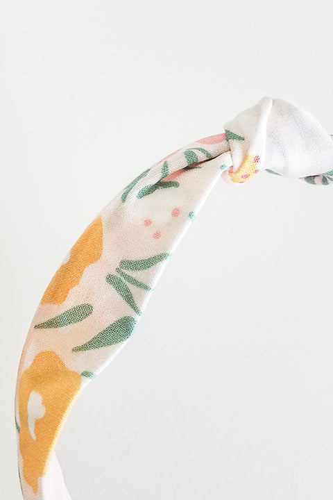 front detail view upcycled handmade headband made from a 100% cotton fabric scraps in a happy floral print with cream, mustard yellow, green and pink