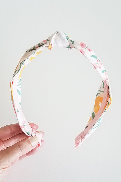 front view of upcycled handmade headband made from a 100% cotton fabric scraps in a happy floral print with cream, mustard yellow, green and pink