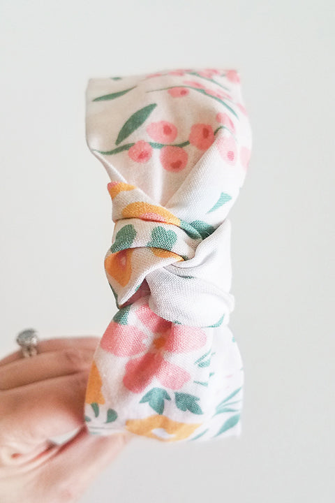 top knot view of upcycled handmade headband made from a 100% cotton fabric scraps in a happy floral print with cream, mustard yellow, green and pink