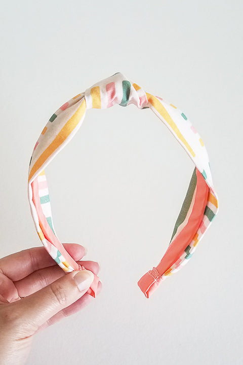 front view upcycled handmade headband made from a 100% cotton fabric scraps in a happy stripes geometric print with cream, mustard yellow, green and pink