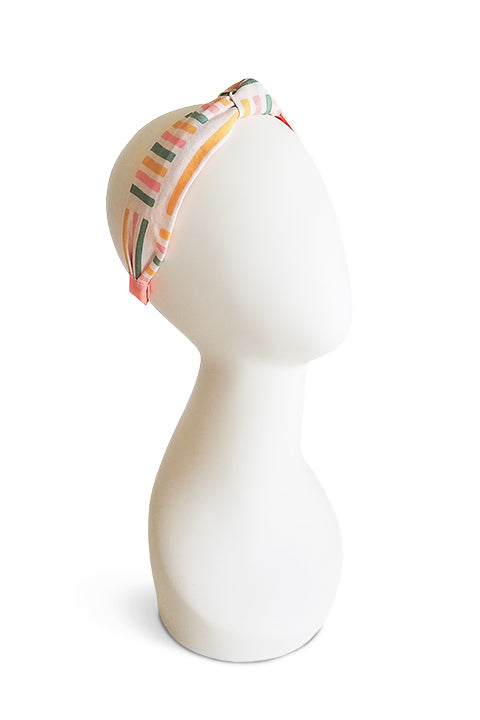 upcycled handmade headband made from a 100% cotton fabric scraps in a happy stripes geometric print with cream, mustard yellow, green and pink. shown on a white model form