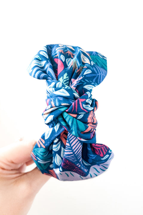 top view of an upcycled cotton fabric headband featuring a top knot and tropical jungle friends animal print fabric