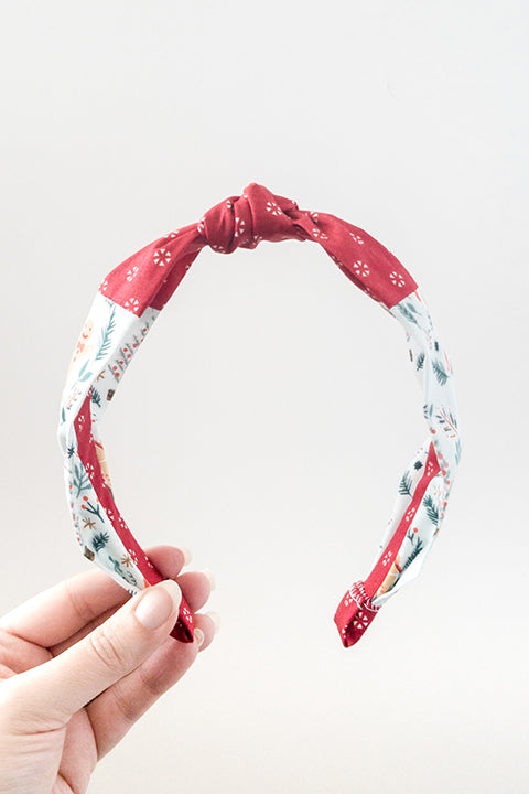 front view of an upcycled cotton fabric headband featuring a top knot and color-blocked prints, one with candy canes and gingerbread and the other a red petite peppermint print