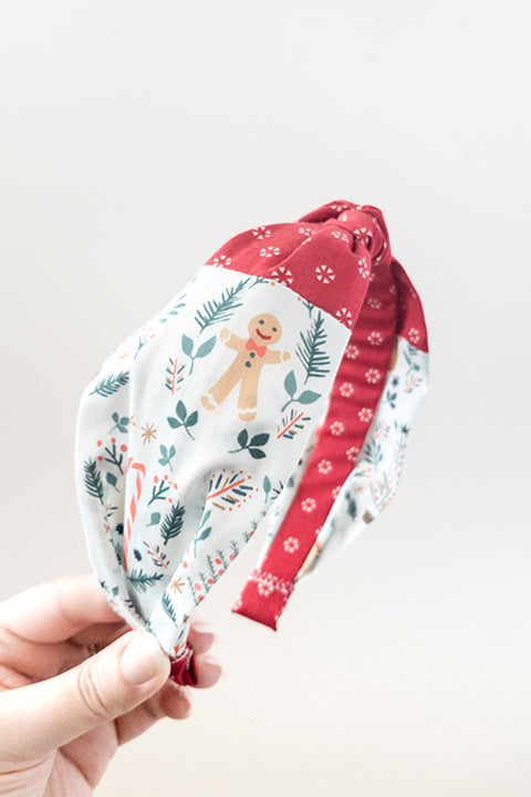 side view of an upcycled cotton fabric headband featuring a top knot and color-blocked prints, one with candy canes and gingerbread and the other a red petite peppermint print