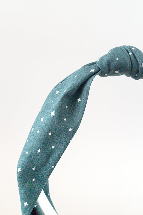 front detail view of an upcycled cotton fabric headband featuring a top knot and forest green holiday starry night print fabric