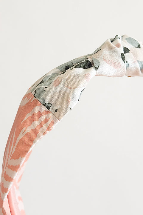 zoomed in detailed view of a two tone top knot style handmade headband. Sustainably made from 100% cotton fabric scraps in two prints, one a pink and sage green watercolor dot floral and the other white ferns on a blush pink background.