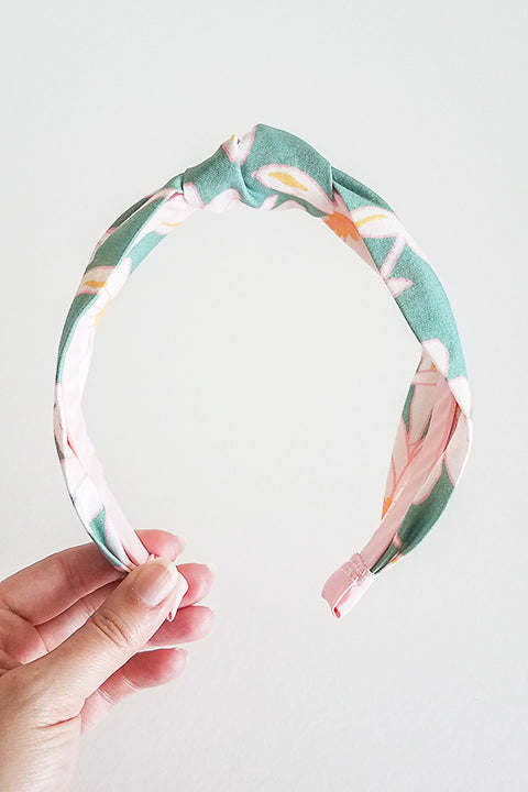 front view of upcycled handmade headband made from a 100% cotton fabric scraps in a verdant floral print with green, cream, pink and mustard.