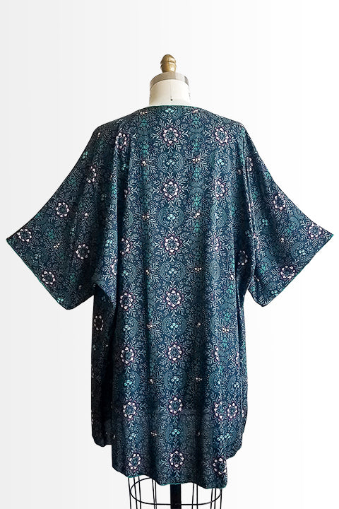 back view of small batch open front fashion kimono made from a 100% rayon midnight blue fabric printed with fireflies and a pink and green floral motif shown on a dress form