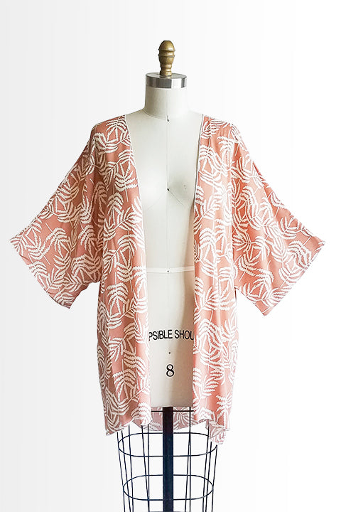 front view of small batch open front fashion kimono made from a 100% rayon cinnamon pink fabric printed with white fern leaves shown on a dress form